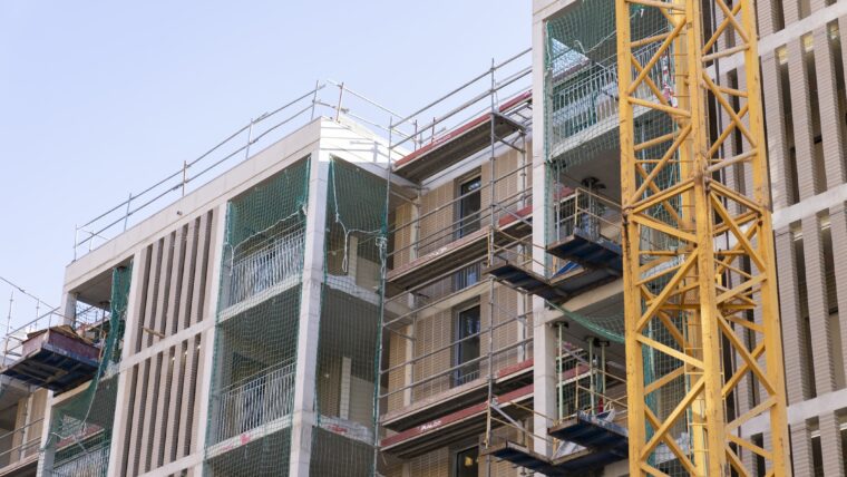 Façana d’una escola en construcció, on es veu una grua i diversos andamiatges.