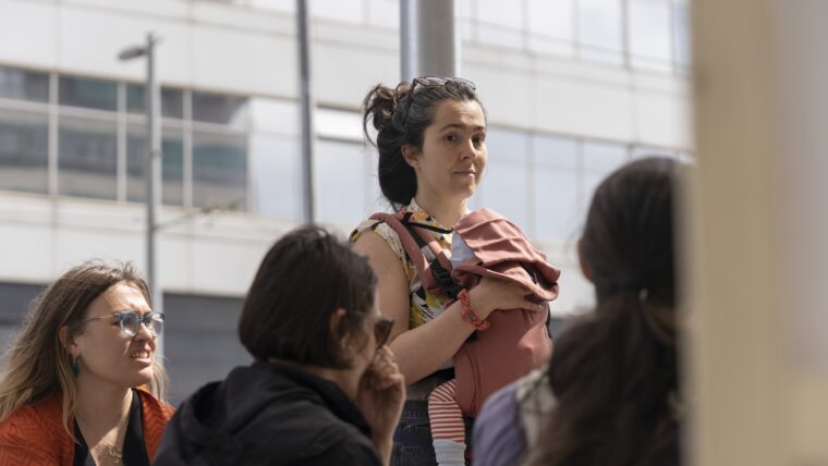 Una dona abraça un infant que subjecta a sobre del seu pit amb una motxilla per portejar.