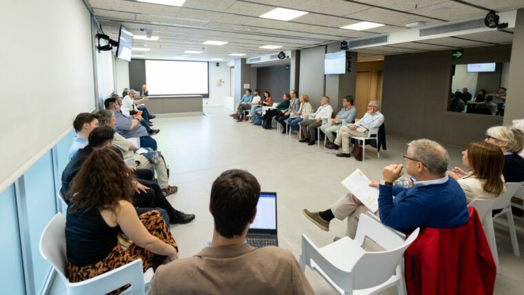 Integrants del grup de treball seuen en cadires al voltant d'una sala